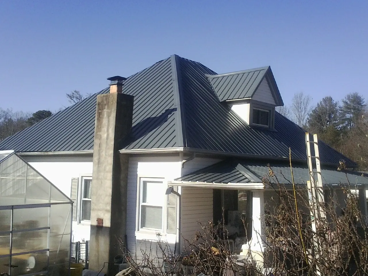 Dark blue standing seam metal roof on a white farmhouse with dormer — Slate & Tile Roof Repair by Roofing Brothers in Hampden