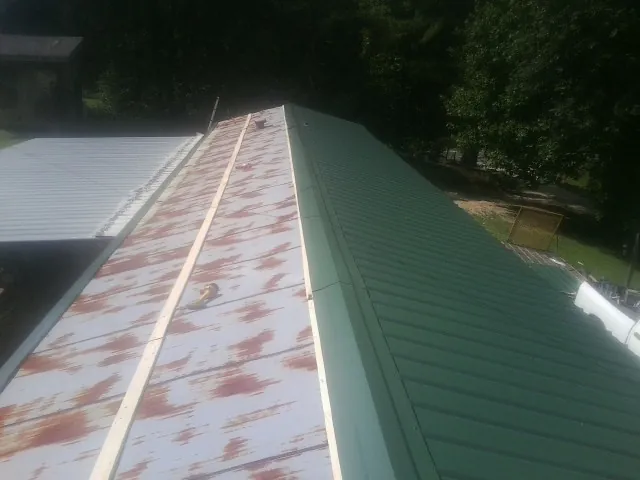 Old rusted panels beside newly installed green metal roofing — Wind Damage Roof Repair by Roofing Brothers in Hampden