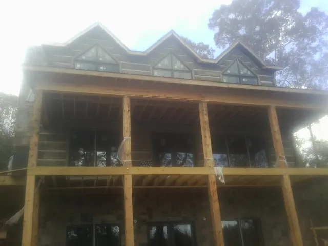 Dormers and porch framing on a large log home under construction — Roof Coating work by our crew in Hampden