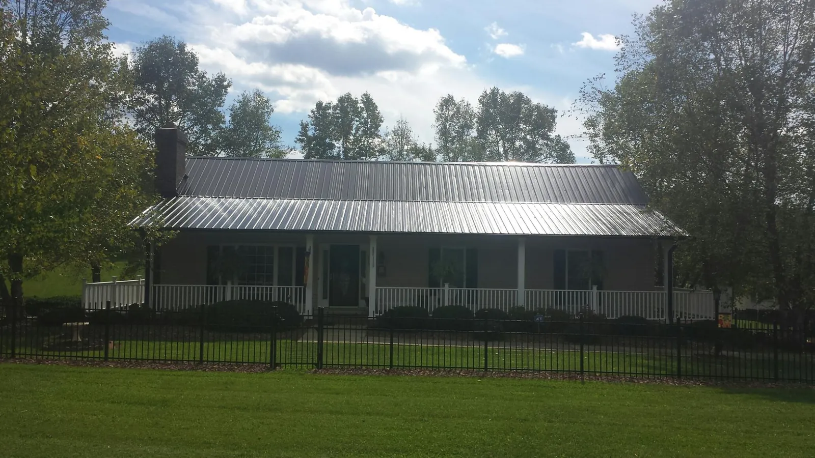 Gray metal roof on a brick ranch with a full width front porch — Gutter Guard Installation work by our crew in Hampden
