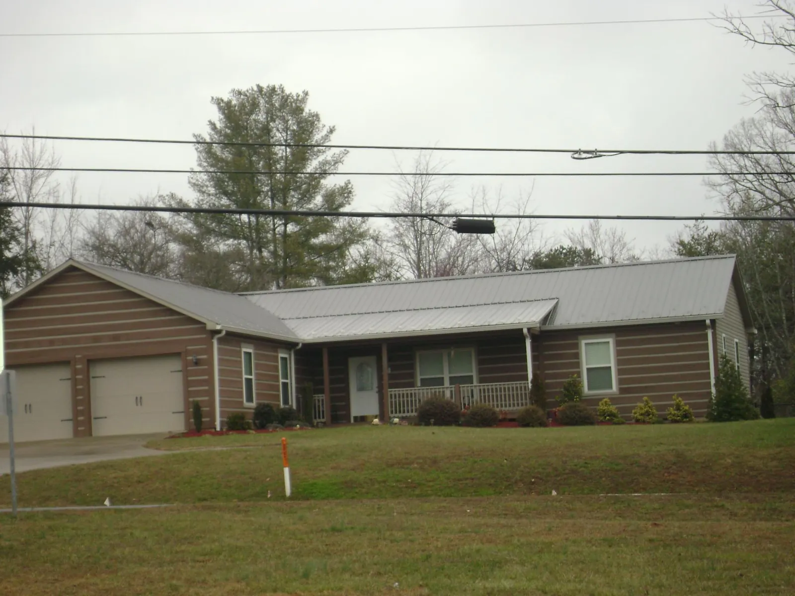 Gray metal roof on a log sided ranch home with a front porch in Hampden