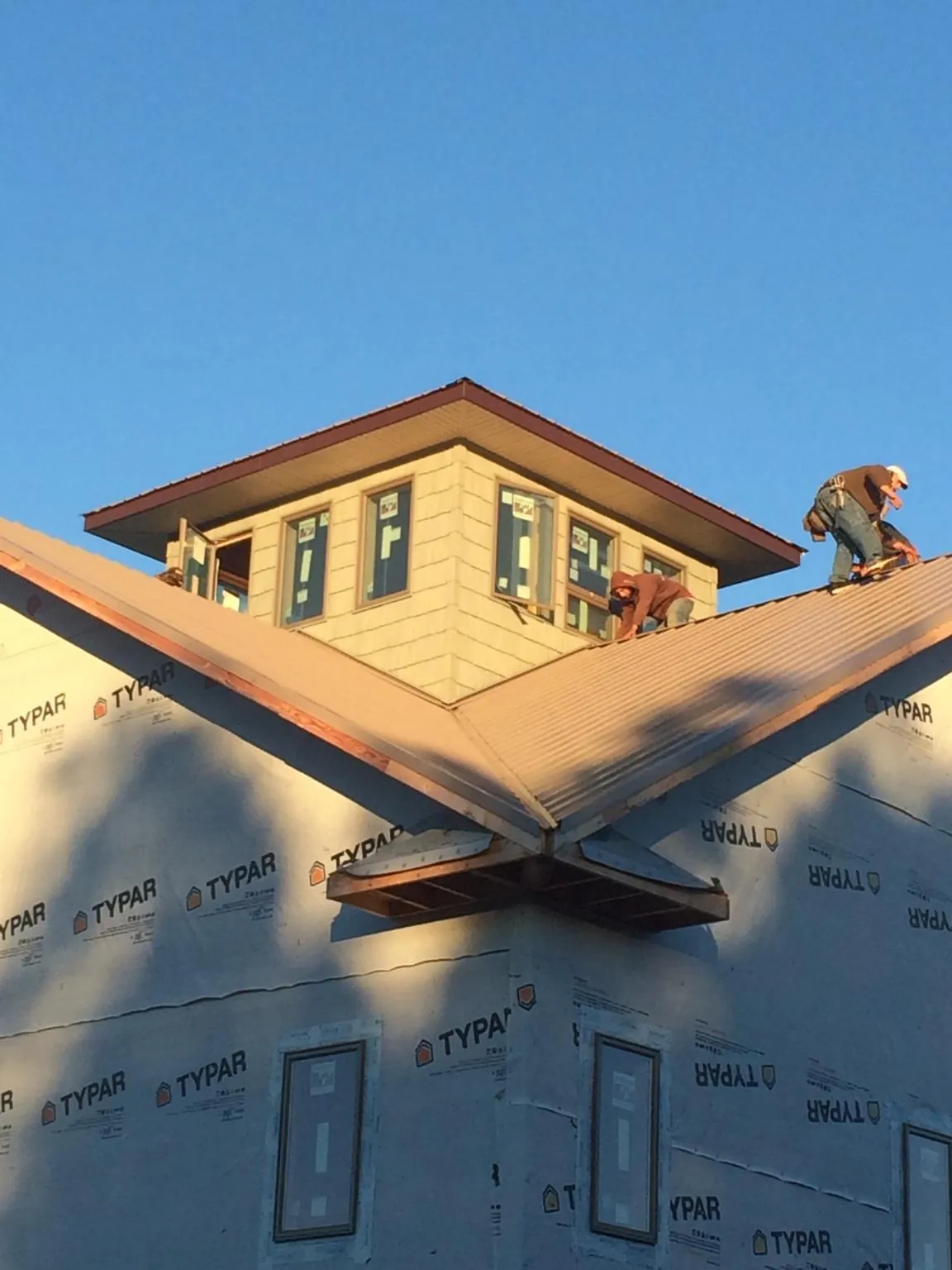 Roofers working around a rooftop cupola on a new metal roof at sunset — Roof Waterproofing in Hampden by Roofing Brothers